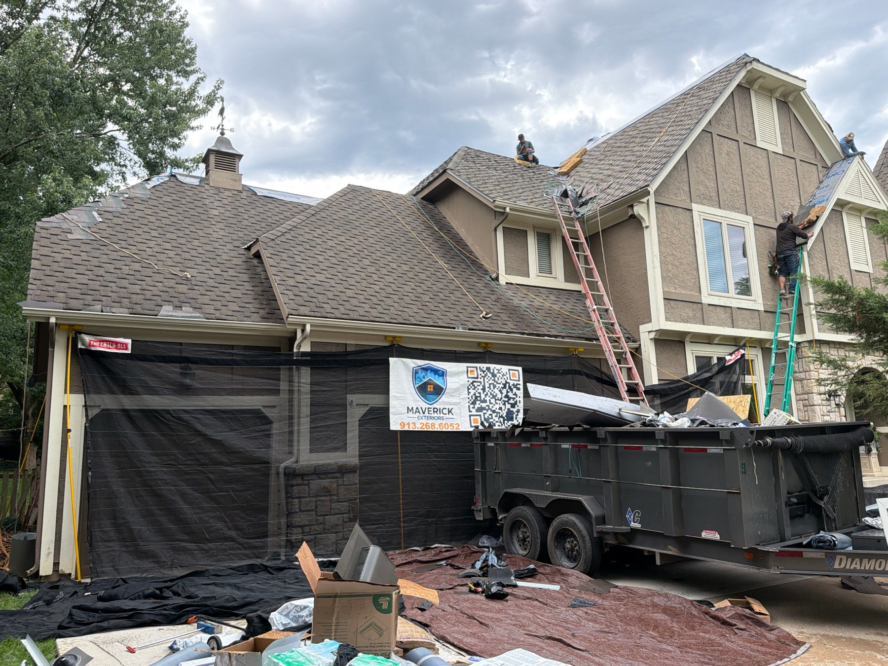 Maverick Exteriors roof replacement crew using catch-all netting and driveway protection on an Overland Park style home.
