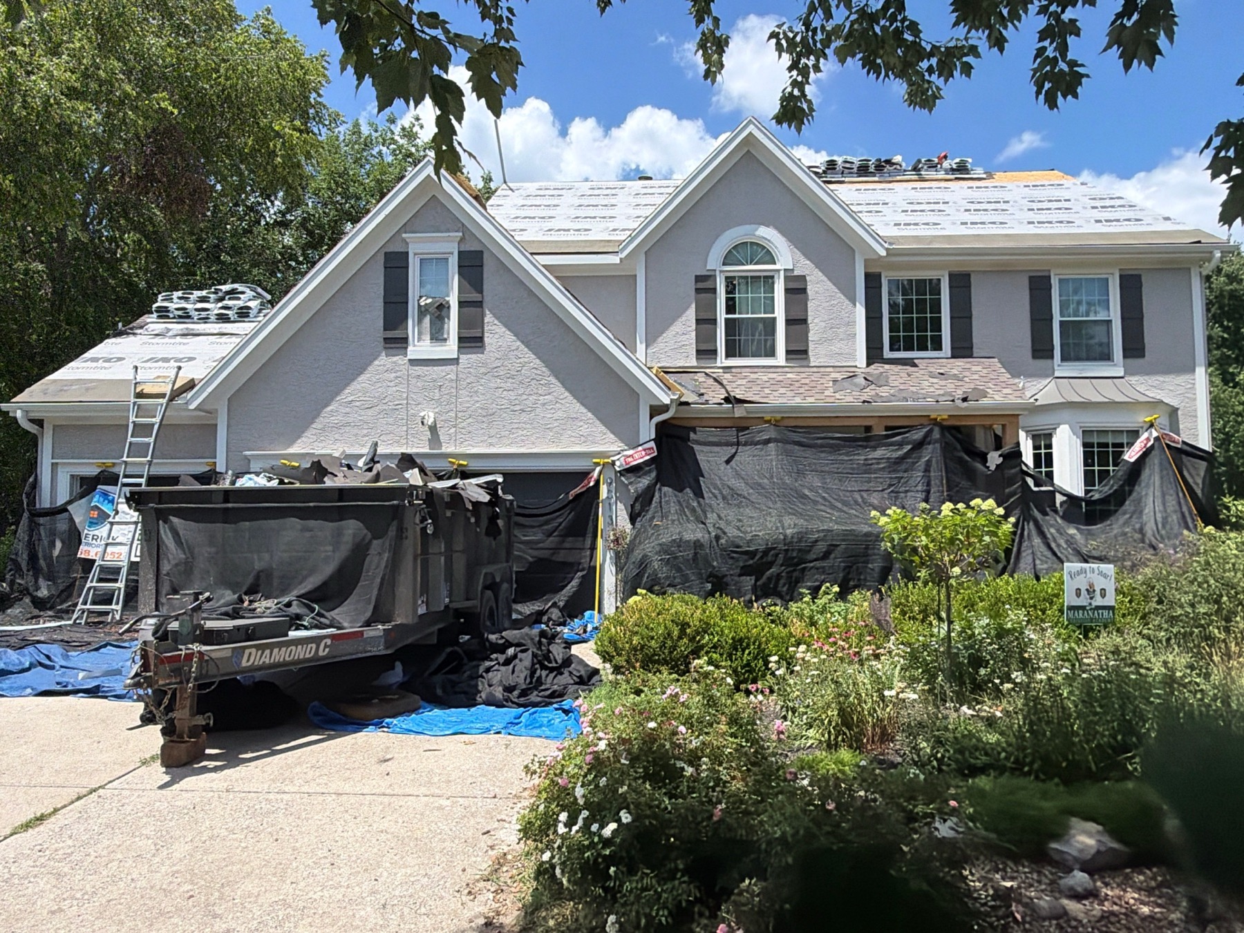 Catch-all protection around landscaping and driveway during roof tear-off on a large home.