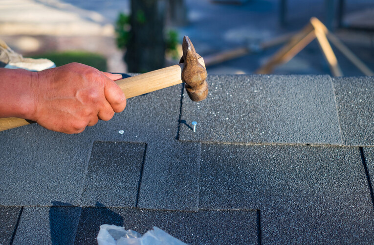 Hand nailing asphalt shingles during a roof replacement in Olathe, KS by Maverick Exteriors.